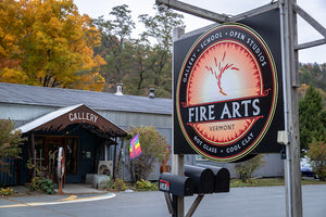 An exterior picture of the Fire Arts Vermont gallery entrance and road sign on Route 30 in Brattleboro, Vermont.