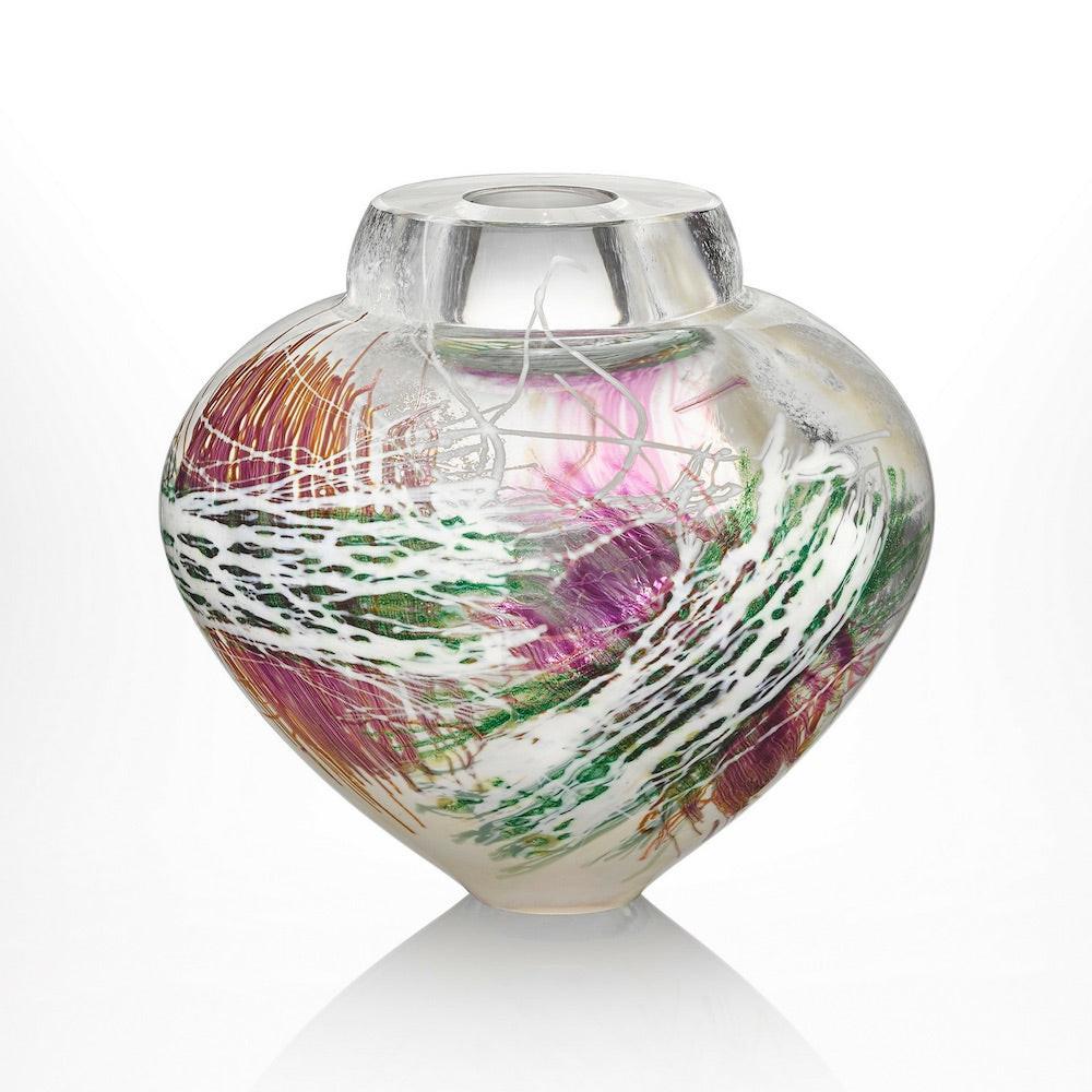 A handcrafted blown glass bowl with layers of colorful glass cane in green, orange, pink, and purple hues, creating a nature-inspired pattern.
