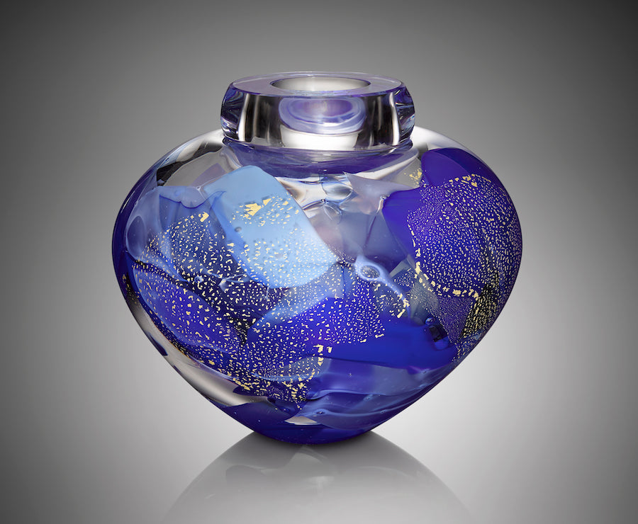 A thick clear hand blown glass vessel features five shades of blue glass with shimmering silver leaf.