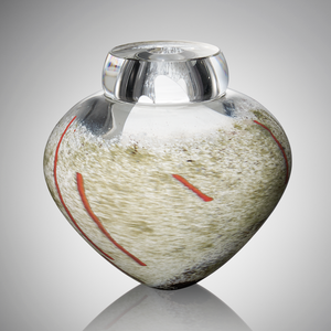 A thick clear hand blown glass vessel featuring subtle shades of gray and white glass with streaks of red glass cane stands against a light gray background.